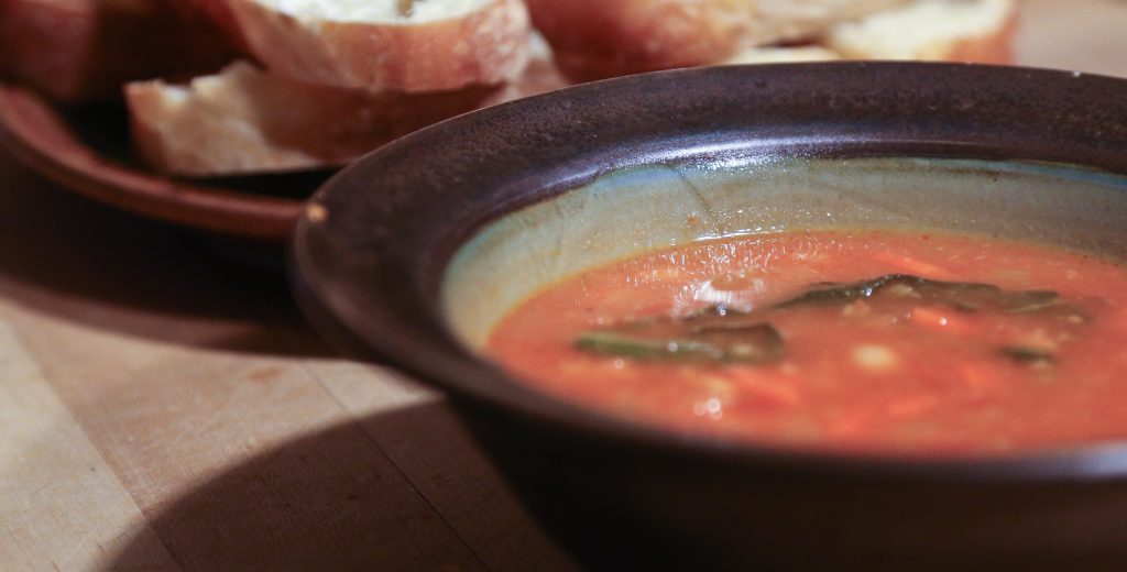 Bowl of soup with bread in the background